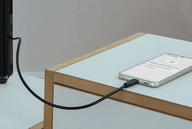 Een mobiele telefoon is via een kabel verbonden met de TV.