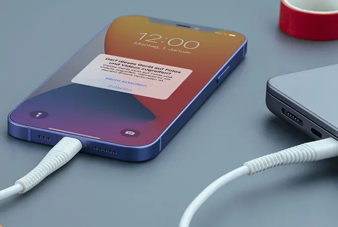 De mobiele telefoon is via een kabel met de notebook verbonden.