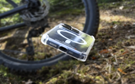 Smartphone in mobiel hoesje valt van de fiets op de bosgrond.